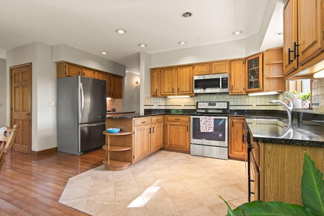 43 W Lynne Ave, Portland, ME 04103 - kitchen with stainless steel appliances, open shelves, backsplash, brown cabinets, and dark stone counters