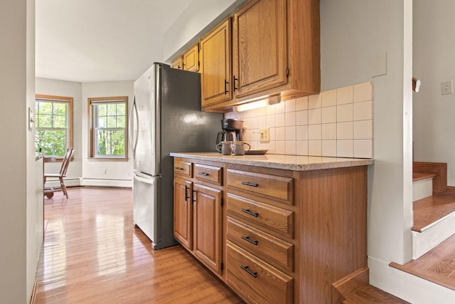 43 W Lynne Ave, Portland, ME 04103 - kitchen featuring light wood-style flooring, brown cabinetry, decorative backsplash, and light stone counters