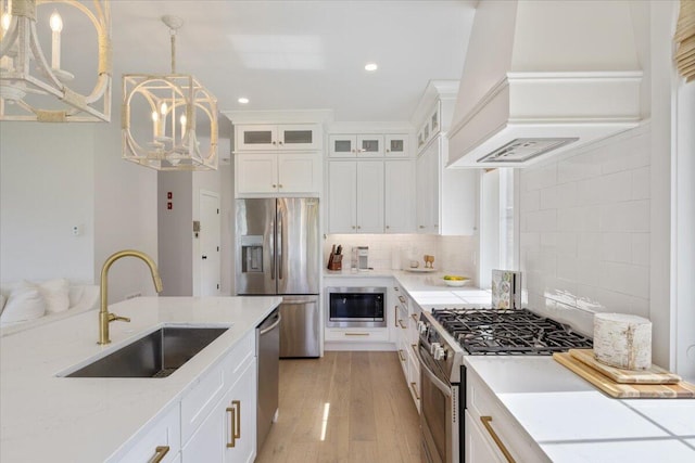 5 Cobblestone St Unit 53, Falmouth, ME 04105 - kitchen featuring appliances with stainless steel finishes, a sink, premium range hood, a chandelier, and white cabinetry