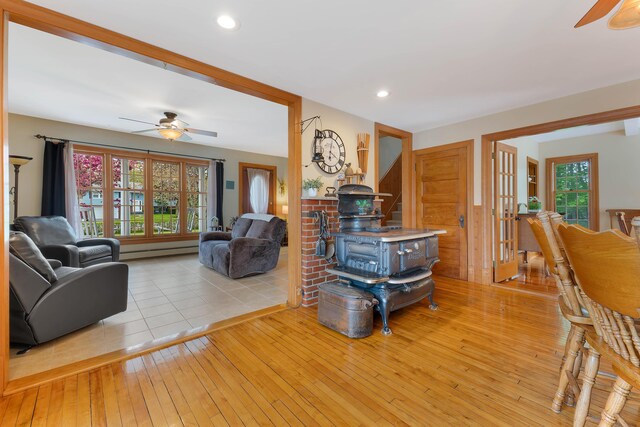 96 Grove St, Lewiston, ME 04240 - living room with ceiling fan, light wood-style flooring, a wood stove, a baseboard radiator, and french doors