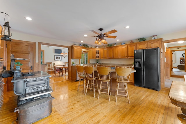 96 Grove St, Lewiston, ME 04240 - kitchen with black fridge with ice dispenser, ceiling fan, light countertops, brown cabinets, and a kitchen bar