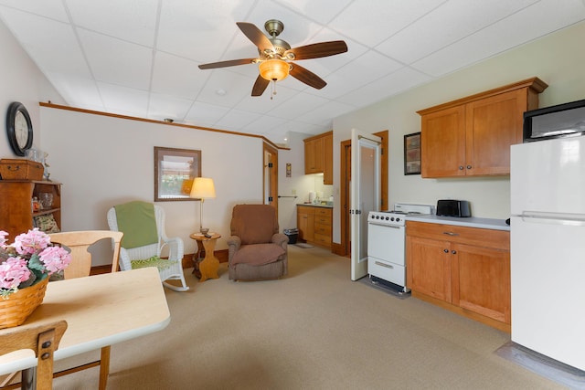 96 Grove St, Lewiston, ME 04240 - kitchen featuring white appliances, ceiling fan, light carpet, brown cabinetry, and light countertops