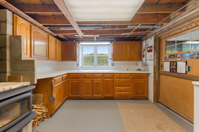 96 Grove St, Lewiston, ME 04240 - kitchen with concrete floors, light countertops, a wood stove, and brown cabinets