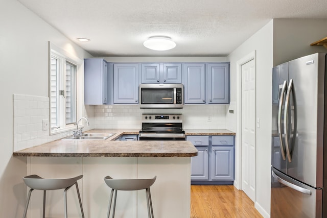 17 Graham Rd Unit 17, Westbrook, ME 04092 - kitchen featuring appliances with stainless steel finishes, a sink, blue cabinetry, a peninsula, and a kitchen breakfast bar