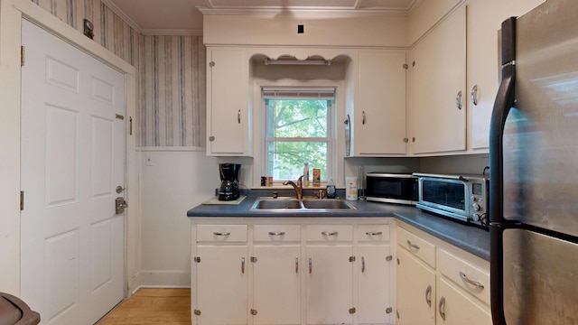 17 Wellman St, Lewiston, ME 04240 - kitchen featuring freestanding refrigerator, a sink, dark countertops, crown molding, and light wood-style floors