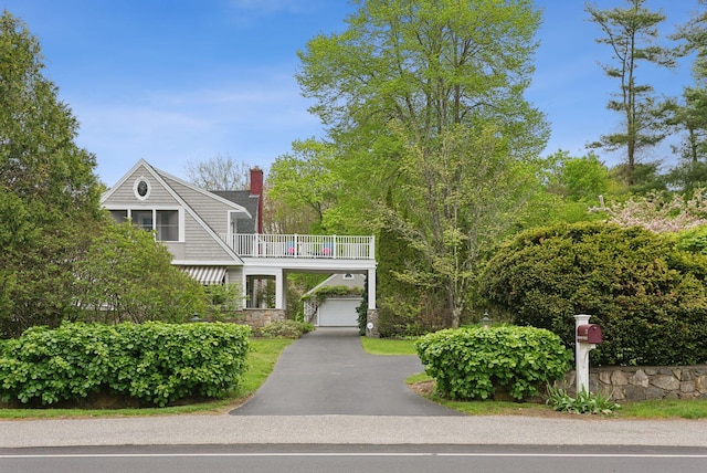 71 N St, Kennebunkport, ME 04046 - view of front of home with a balcony, driveway, stone siding, a garage, and a chimney