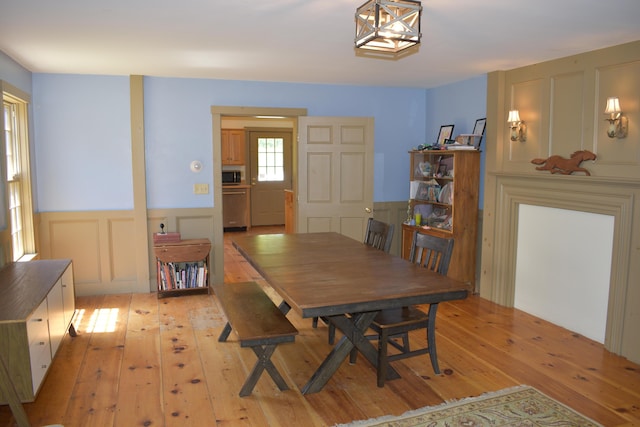 306 Campbell Rd, Leeds, ME 04263 - dining room with light wood-type flooring, a wainscoted wall, and a decorative wall
