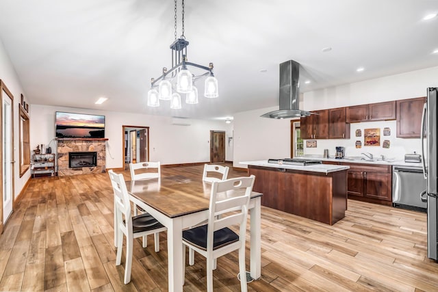 66 Mcnally Rd, Clinton, ME 04927 - dining space with light wood-style floors, a stone fireplace, a chandelier, and recessed lighting