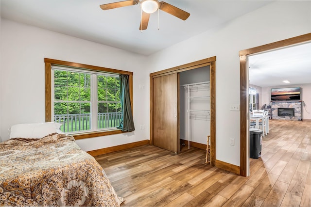 66 Mcnally Rd, Clinton, ME 04927 - bedroom featuring light wood-type flooring, baseboards, a stone fireplace, a closet, and ceiling fan