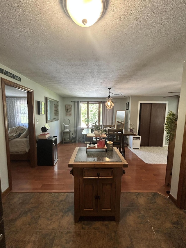 208 New Rd, Arundel, ME 04046 - kitchen featuring a textured ceiling, a center island, dark countertops, dark tile patterned floors, and hanging light fixtures