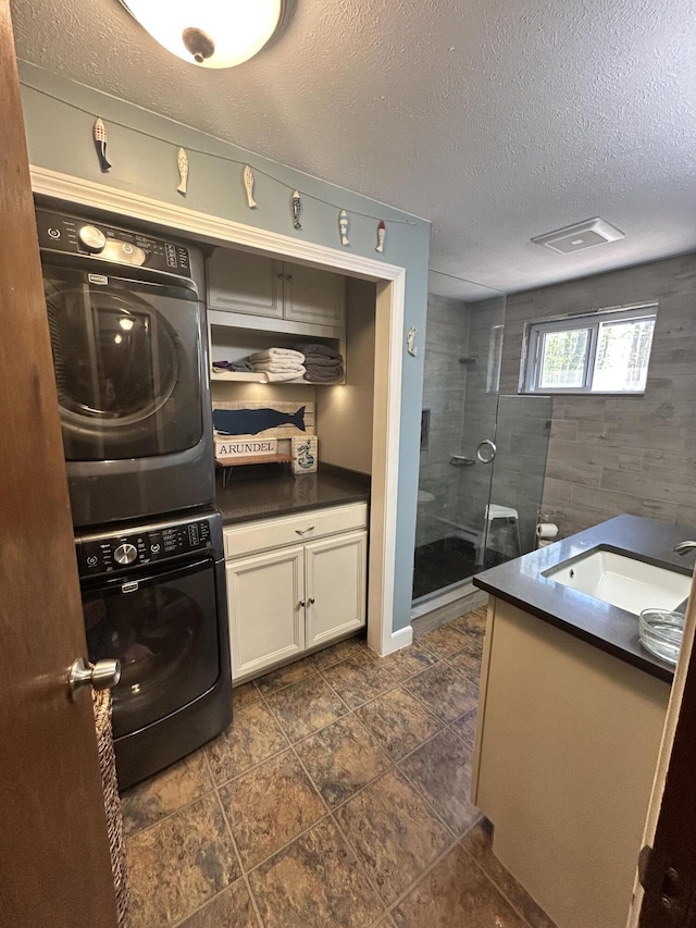 208 New Rd, Arundel, ME 04046 - kitchen featuring stacked washer / drying machine, dark countertops, a sink, a textured ceiling, and white cabinets