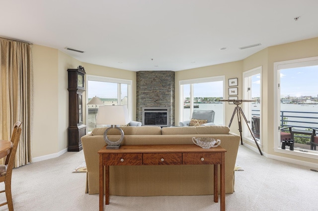 215 High St Unit 101, South Portland, ME 04106 - living room featuring light colored carpet, a stone fireplace, a water view, and baseboards