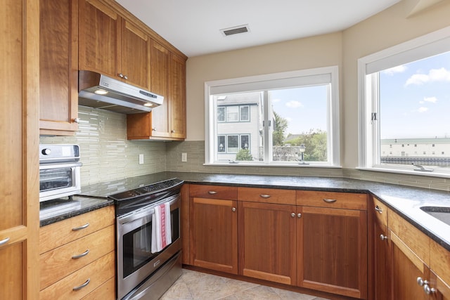 215 High St Unit 101, South Portland, ME 04106 - kitchen with stainless steel electric range oven, under cabinet range hood, backsplash, and brown cabinetry