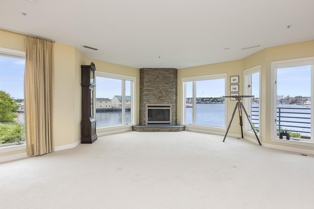 215 High St Unit 101, South Portland, ME 04106 - unfurnished living room featuring light carpet, a water view, a stone fireplace, and healthy amount of natural light