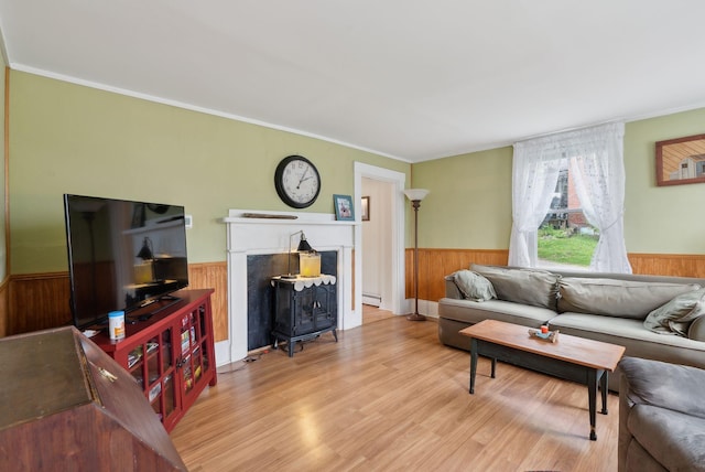 19 Cobbossee Ave, Gardiner, ME 04345 - living area with a wainscoted wall, wood walls, a wood stove, wood finished floors, and ornamental molding