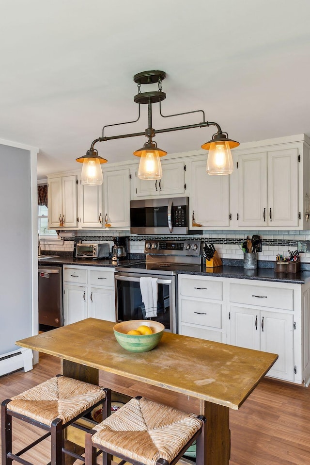 19 Cobbossee Ave, Gardiner, ME 04345 - kitchen with appliances with stainless steel finishes, decorative backsplash, dark countertops, and light wood-style floors