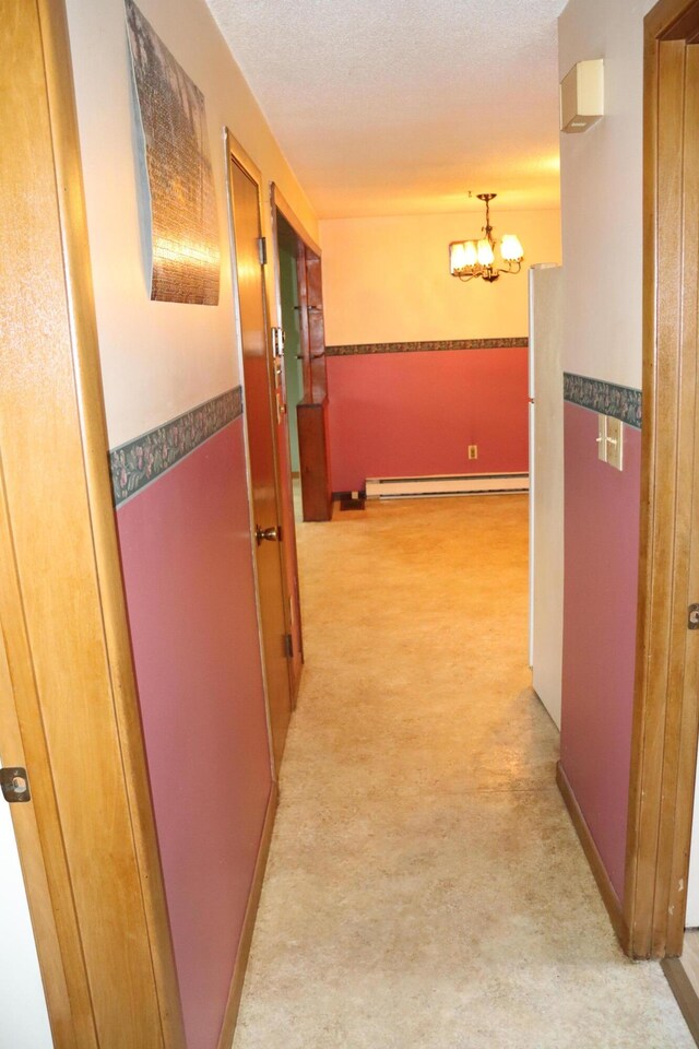 113 Pleasant St, Greenville, ME 04441 - hallway with a baseboard radiator, a chandelier, and light carpet