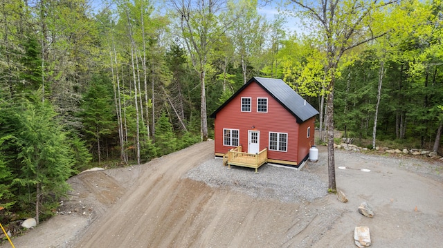 23 Bray Cir, Passadumkeag, ME 04475 - rustic home featuring dirt driveway, a view of trees, a deck, and metal roof