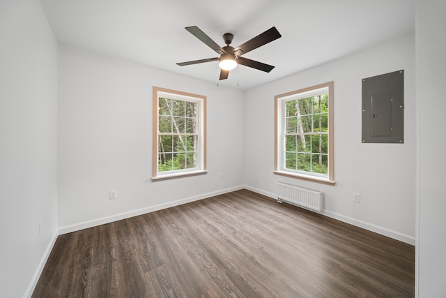 23 Bray Cir, Passadumkeag, ME 04475 - empty room featuring radiator heating unit, electric panel, plenty of natural light, and dark wood finished floors