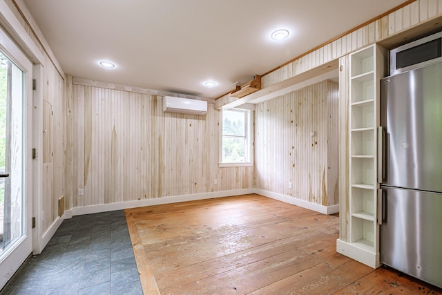 76 Old W Bethel Road, Albany Twp, ME 04217 - spare room featuring a wall mounted AC, wooden walls, baseboards, and hardwood / wood-style flooring