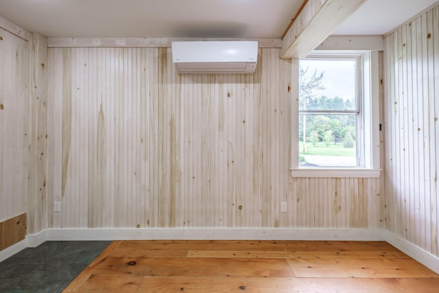 76 Old W Bethel Road, Albany Twp, ME 04217 - empty room featuring a wall mounted air conditioner, wood-type flooring, baseboards, and wood walls