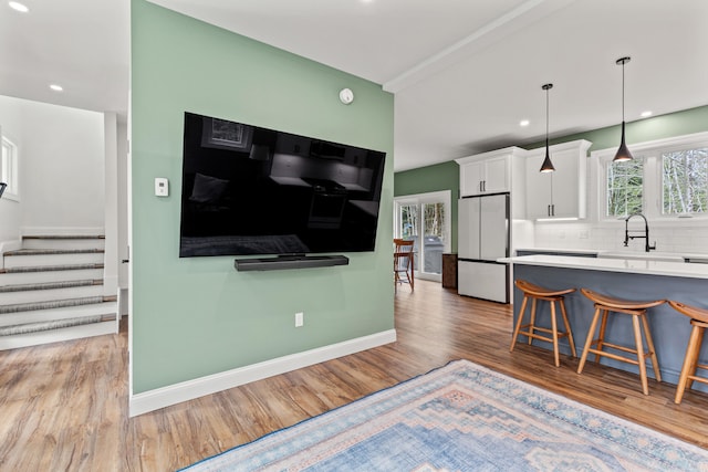 64 Autumn Rdg, Sabattus, ME 04280 - kitchen with freestanding refrigerator, light wood finished floors, white cabinetry, a kitchen breakfast bar, and baseboards