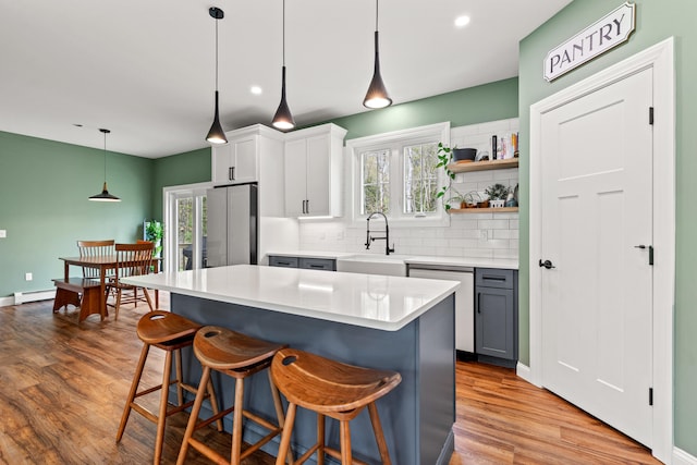 64 Autumn Rdg, Sabattus, ME 04280 - kitchen featuring stainless steel appliances, a sink, wood finished floors, tasteful backsplash, and a breakfast bar area