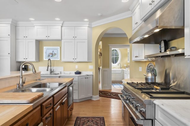 50 Higbee Ln, Boothbay, ME 04571 - kitchen with stainless steel range, under cabinet range hood, a sink, arched walkways, and light wood-type flooring