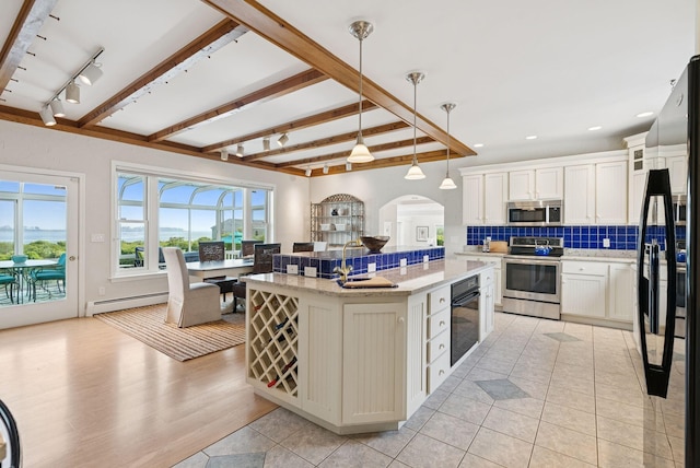 25 Ocean Ave, Cape Elizabeth, ME 04107 - kitchen featuring black appliances, tasteful backsplash, baseboard heating, a center island, and arched walkways