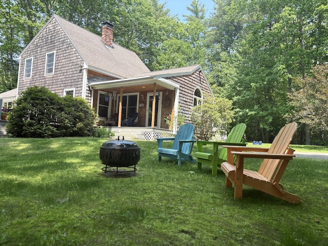 282 Pierces Point Rd, Windsor, ME 04363 - rear view of property featuring a fire pit, a lawn, a shingled roof, and a chimney