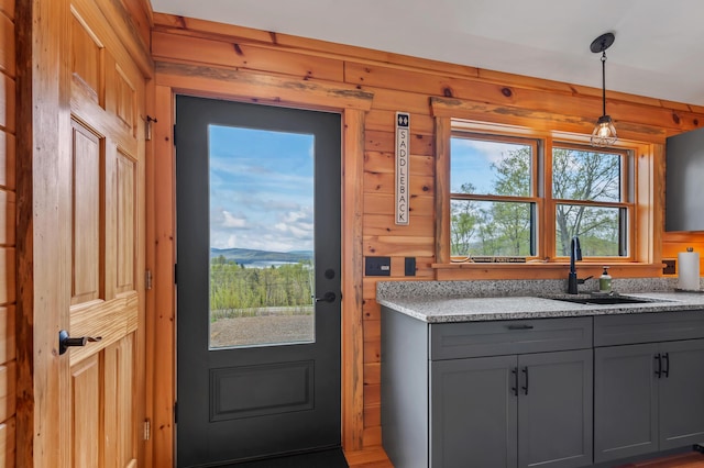 3935 Main St, Rangeley, ME 04970 - kitchen featuring gray cabinets, a sink, wooden walls, pendant lighting, and light stone countertops