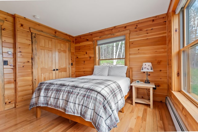 3935 Main St, Rangeley, ME 04970 - bedroom featuring a baseboard heating unit, wood finished floors, multiple windows, wood walls, and a closet