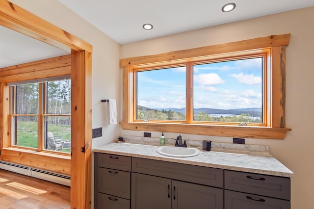 3935 Main St, Rangeley, ME 04970 - bathroom with a baseboard heating unit, wood finished floors, a mountain view, recessed lighting, and vanity