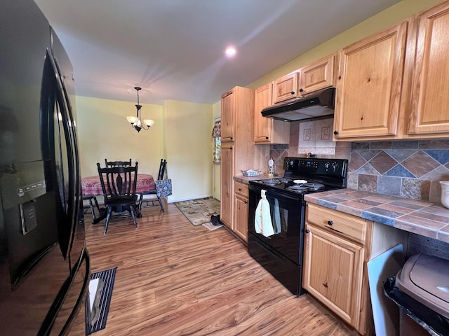 13 Pearl St, Fort Kent, ME 04743 - kitchen featuring black appliances, under cabinet range hood, light brown cabinetry, tile countertops, and a chandelier