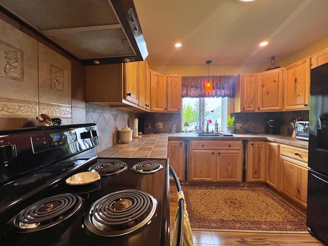 13 Pearl St, Fort Kent, ME 04743 - kitchen with black appliances, tile counters, a sink, ventilation hood, and tasteful backsplash