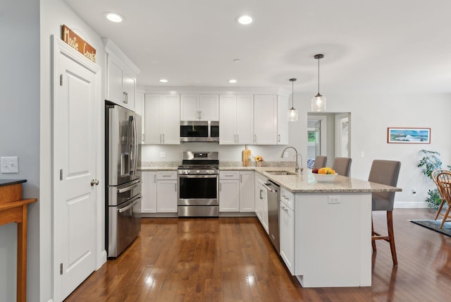 45 S Ridge Rd, Falmouth, ME 04105 - kitchen featuring appliances with stainless steel finishes, a peninsula, a sink, a kitchen breakfast bar, and white cabinets