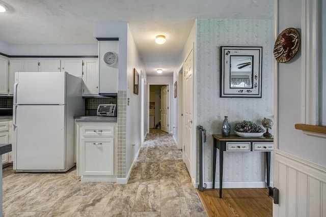 19 Rumery Rd, Lyman, ME 04002 - kitchen with freestanding refrigerator, white cabinets, wallpapered walls, and decorative backsplash