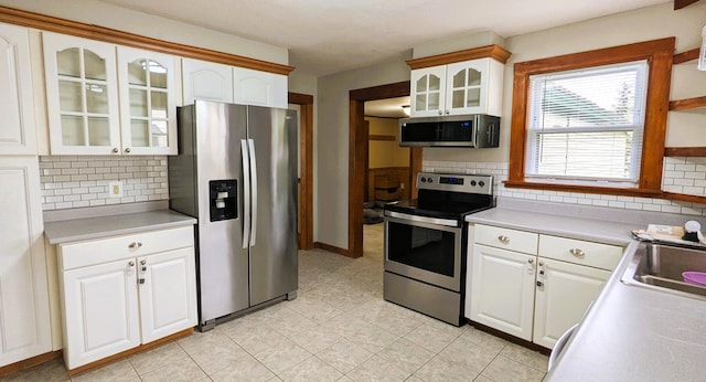 191 Bates St, Pittsfield, ME 04967 - kitchen featuring appliances with stainless steel finishes, tasteful backsplash, light tile patterned floors, glass insert cabinets, and white cabinets