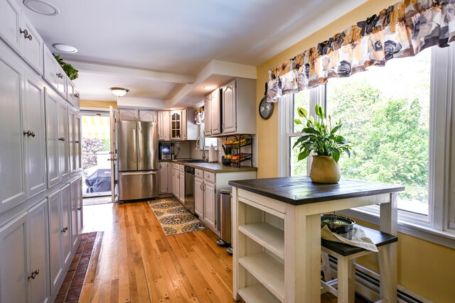 77 Carter St, Portland, ME 04103 - kitchen with stainless steel appliances, dark countertops, a sink, light wood-style flooring, and glass insert cabinets