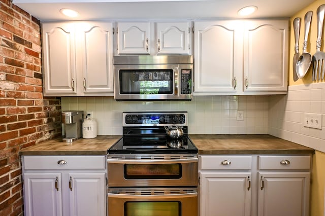 77 Carter St, Portland, ME 04103 - kitchen featuring stainless steel appliances, wood counters, white cabinets, backsplash, and brick wall