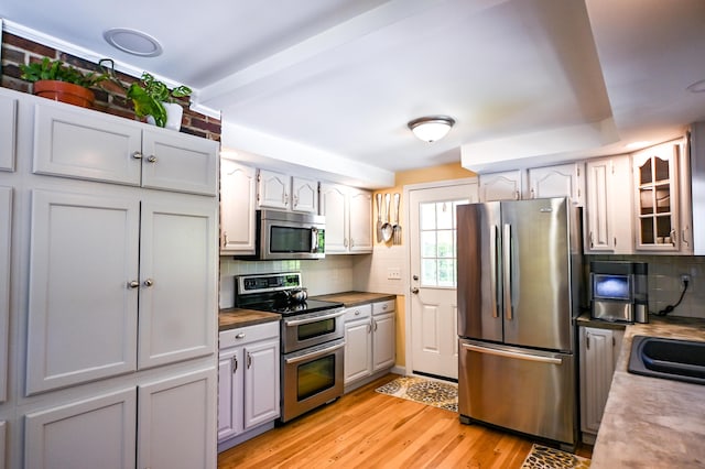77 Carter St, Portland, ME 04103 - kitchen featuring stainless steel appliances, backsplash, light wood-style flooring, and glass insert cabinets