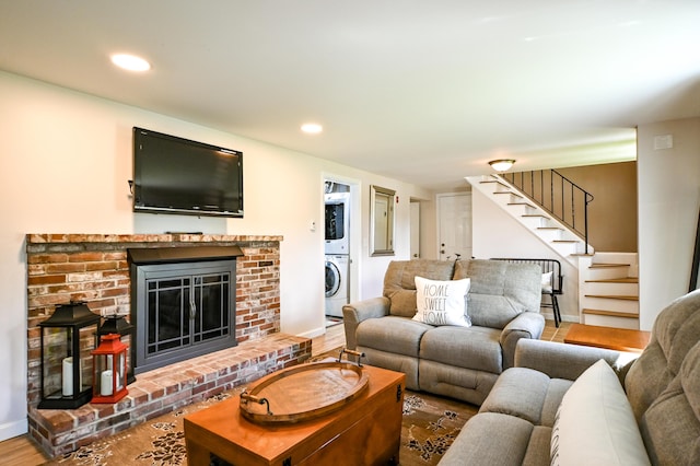 77 Carter St, Portland, ME 04103 - living room featuring estacked washer and dryer, stairs, a brick fireplace, baseboards, and wood finished floors