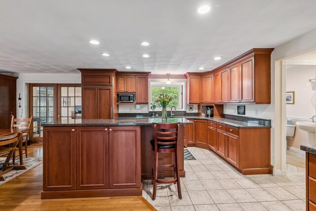 3 Payneton Hill Rd, York, ME 03909 - kitchen with stainless steel microwave, recessed lighting, a center island, dark stone counters, and brown cabinets