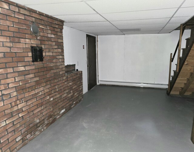 60 Rolling Rdg, Jay, ME 04239 - finished basement featuring brick wall, stairs, a baseboard radiator, and a drop ceiling