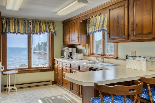16 Tilton Ln, Southport, ME 04576 - kitchen featuring light countertops, baseboard heating, a peninsula, brown cabinets, and white microwave