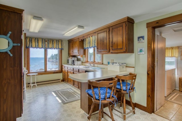 16 Tilton Ln, Southport, ME 04576 - kitchen featuring light countertops, baseboard heating, a breakfast bar area, a peninsula, and white microwave