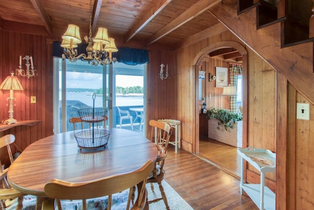 16 Tilton Ln, Southport, ME 04576 - dining room with wooden walls, wooden ceiling with exposed beams, wood finished floors, arched walkways, and a chandelier