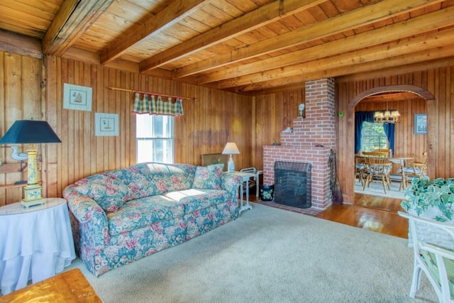 16 Tilton Ln, Southport, ME 04576 - carpeted living room with plenty of natural light, a chandelier, wooden walls, a fireplace, and arched walkways