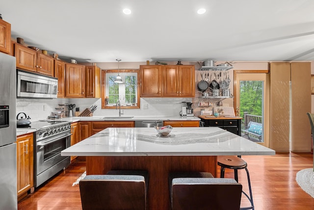 27 Wilmer Chase Rd, North Berwick, ME 03906 - kitchen featuring appliances with stainless steel finishes, a sink, a kitchen bar, tasteful backsplash, and light wood-style flooring