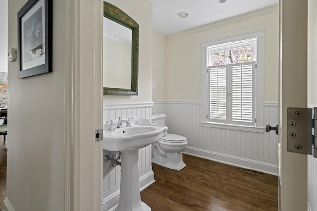52 Lester B Orcutt Blvd, Biddeford, ME 04006 - bathroom with toilet, a wainscoted wall, wood finished floors, and ornamental molding